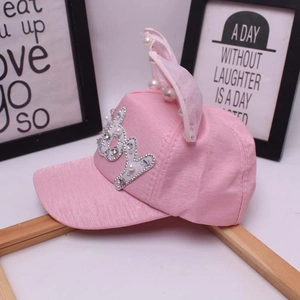 Dettaglio del cappellino rosa per bambina con perle, lettere in strass e orecchie