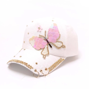 Casquette blanche avec écusson papillon à paillettes et anneaux métalliques sur fond pur