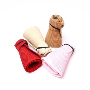 Folded straw visors in red, beige, brown, and pink showcasing portable roll-up design
