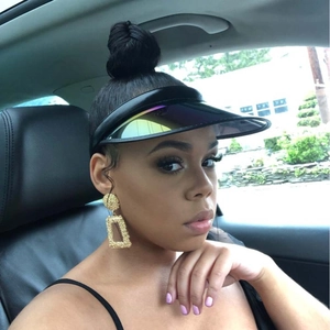 Close-up of model wearing holographic PVC sun visor and large textured gold square earrings