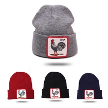 Détail du patch coq coloré et des lettres COCK sur le bonnet en tricot pour enfants