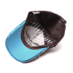 Detail view of frayed baseball cap edges with inside wash label and blue brim stitching