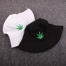 Detail view of cotton bucket hats in black and white with green leaf embroidery