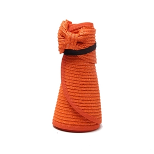 Detail of rollable orange straw hat showing woven texture and bow with elastic strap