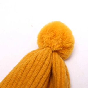 Vue détaillée du bonnet en maille jaune gingembre avec un pompon en fausse fourrure