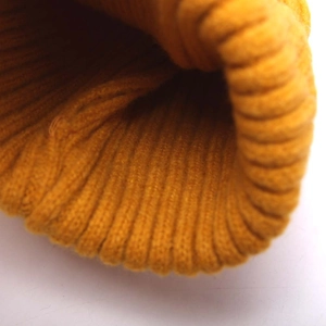 Gros plan sur la texture en maille côtelée jaune gingembre d'un bonnet enfant
