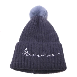 Détail du bonnet en tricot bleu marine avec pompon bleu clair et broderie cursive blanche