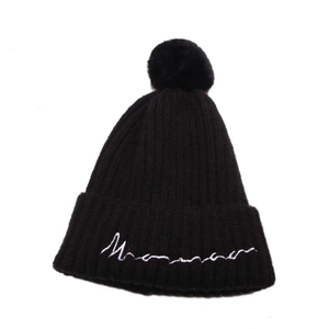 Détails de la maille et broderie blanche sur un bonnet d'hiver noir avec pompon doux