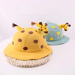 Dettaglio di cappelli da sole a giraffa per neonati in giallo e blu su tappeto