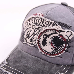 Detail of shark embroidery and distressed washed fabric on this dark gray baseball cap