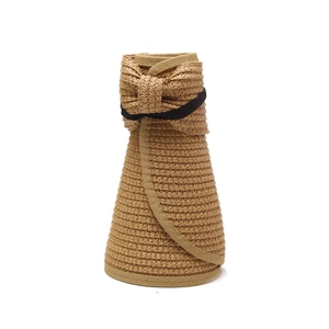 Detail of a foldable khaki straw sun hat with an elegant bow and black elastic strap