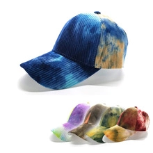 Detail showing various colors of tie-dye corduroy baseball caps in a stack
