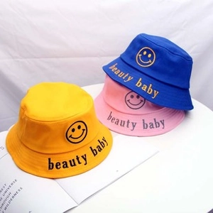 Dettaglio di cappelli da sole in cotone giallo, rosa e blu con toppa con faccina