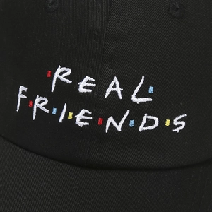 Detailed close-up of REAL FRIENDS 3D embroidery on black cotton baseball cap fabric