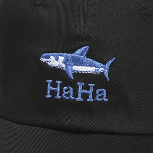 Close-up of embroidered shark and HaHa letters on black cotton twill baseball cap