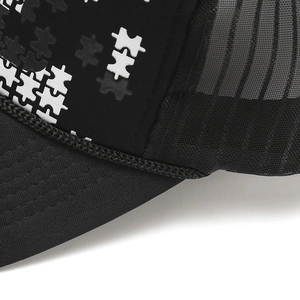 Detail of black and white trucker hat featuring mesh back and puzzle pattern printing