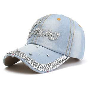 Détail d'une casquette en jean bleu clair avec patch Love en strass et cristaux brillants