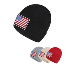 Detail view of American flag patches on four colors of ribbed knit beanies for adults