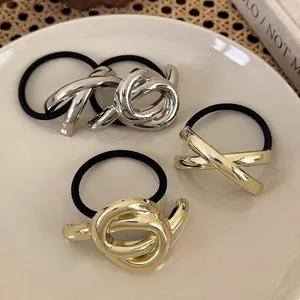 Set aus minimalistischen Gold- und Silberknoten-Haargummis auf einem Keramiktablett