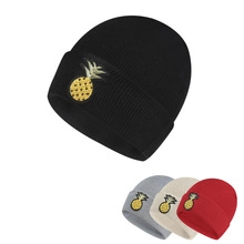 Detailed close-up showing four colors of knitted beanies with pineapple embroidery