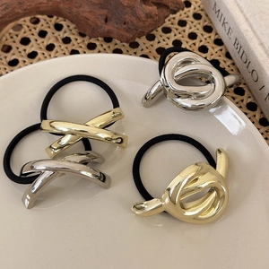 Minimalistische Haargummis in Gold und Silber mit geometrischem Knoten auf einem Porzellan