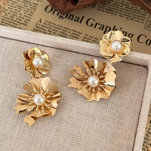 French vintage metallic flower earrings with centered white pearls on a woven tray