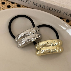 Close-up of gold and silver hammered metal charms on high-elasticity hair ties