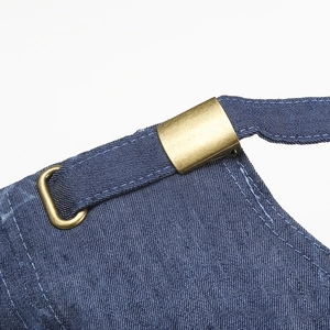 Detail of blue denim apron with adjustable brass metal buckle and white double stitching