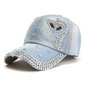 Dettaglio del berretto da baseball in denim azzurro con cigno di strass e borchie argento