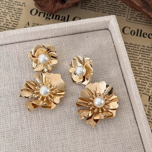 Detail of gold floral earrings set featuring layered petals and white pearls on tray