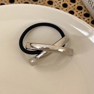Nahaufnahme des minimalistischen Haargummis mit silbernem X-Metall-Detail auf Teller