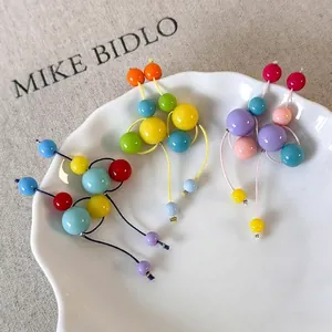 Boucles d'oreilles pendantes en perles de résine colorées sur une assiette blanche