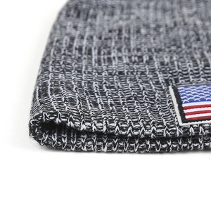 Detail of grey knitted winter hat featuring an American flag patch and thick knit texture