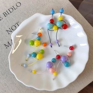 Trois paires de boucles d'oreilles en résine colorée sur un plateau en céramique blanc