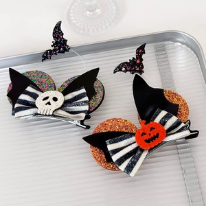 Detail of Halloween hair clips with pumpkin and skull sequins on striped bows
