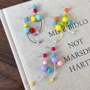 Détail de boucles d'oreilles pendantes en perles de résine colorées sur un livre en tissu