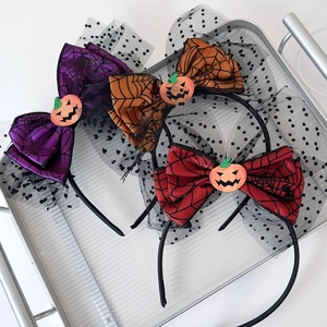 Detail of three Halloween headbands with spider web bows and pumpkins in a silver tray