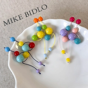 Détail de boucles d'oreilles en perles de résine colorées sur une assiette en céramique