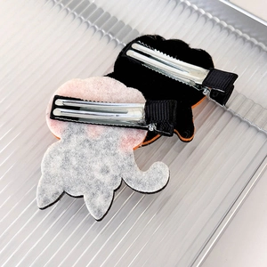 Detail of children's Halloween hair clips with black felt and white plush textures