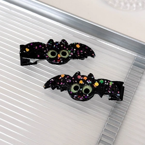 Detail of bat-shaped Halloween hair clips with colorful sequins and black ribbon lining