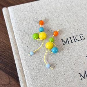 Détail macro de boucles d'oreilles en résine aux couleurs vives et design à pampilles