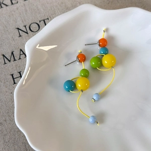 Détail de boucles d'oreilles pendantes en perles de résine colorées sur une assiette