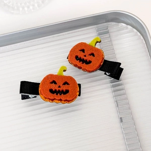 Detail of orange felt pumpkin hair clips with green stems and black grosgrain ribbon base