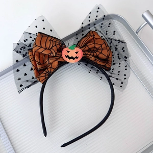 Detail of Halloween headband with orange spiderweb bow, pumpkin face, and black polka dot mesh