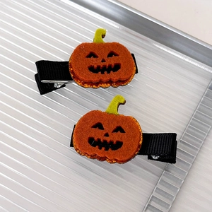 Detail of Halloween pumpkin hair clips made of felt and orange sequins on a tray