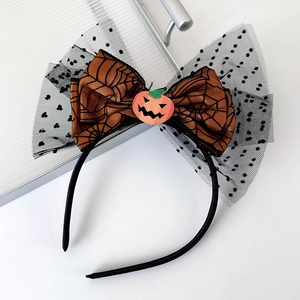 Detail of Halloween headband with orange spider web bow, pumpkin face and black polka dot veil