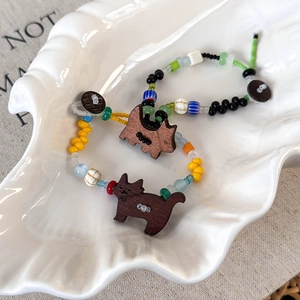 Détail de bracelets en perles colorées avec pendentifs chat en bois sur plateau