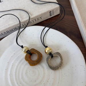 Close-up of vintage camel bone pendant necklace with crackle glaze and gold bead details