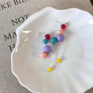 Gros plan de boucles d'oreilles pendantes en perles de résine multicolores sur un plateau