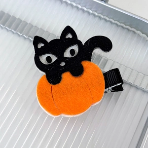 Detail view of felt Halloween hair clip featuring a black cat and orange pumpkin on metal clip